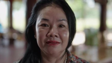 Asyalı Vietnamlı olgun bir kadının portresi kameraya gülümseyen uzun düz saçlı ve boyalı dudaklı - 4K yatay video