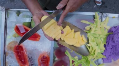 Bangkok Tayland 'da sokakta büyük bir bıçakla taze meyveyi kesen ellerin yakın çekimi - 4K Yatay Video
