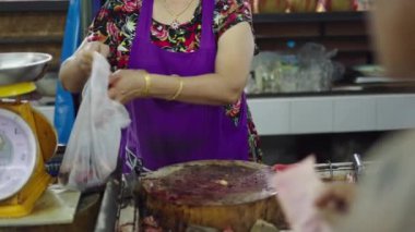 Ağır çekim Asyalı olgun kadın balık dükkanında çiğ balıkla çalışıyor. 4K yatay video.
