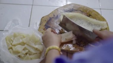 Ahşap bir masada büyük bir bıçakla tavuk eti kesen bir kasabın ellerini yakın plan 4K yatay video.