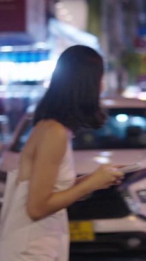 Güzel bir kadın elinde cep telefonuyla karşıdan karşıya geçiyor - FullHD dikey video