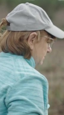 Şarapları elektrikli makasla budarken üzüm bağında konuşan kıdemli beyaz kadın ve erkek.