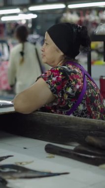 Yerel bir marketteki Asyalı kadın, tartılmayı beklerken kameraya bakıyor. FullHD dikey video.