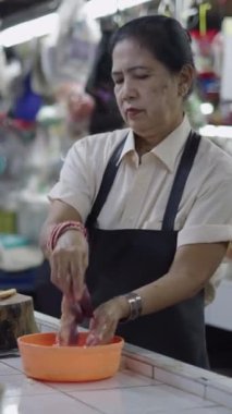 Yavaş çekimde kadın kasap, yerel markette satmadan önce bir tavuğun organlarını yıkıyor ve kurutuyor.