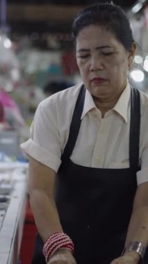 Asyalı kasap bir tavuğun iç organlarını bıçakla çıkarıyor ve onları markette satmak için suyla yıkıyor.