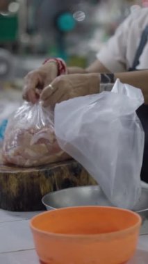 Asyalı bir kasap, ahşap bir torba içinde kesilmiş tavuk eti siparişi veriyor.