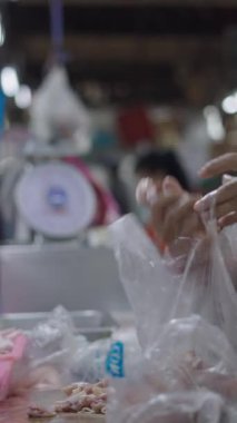 Marketteki kasap kadın önceden kesilmiş ve hazırlanmış tavuk etini plastik bir torbaya koyar.