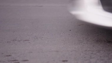 Otomobil ve motosikletlerin tekerleklerinin döndüğü asfaltlı sokak - 4K Yatay Video