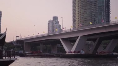 Bangkok Thathand 'daki Chao Reynaya nehri. Şehrin ufuk çizgisindeki köprünün altında çok sayıda tekne taksisi dolaşıyor. 4K Yatay