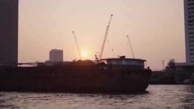 Tayland 'da Bangkok' ta gün batımında kum mavnası. Şehir silüeti ve Chao the River limanı - 4K Yatay