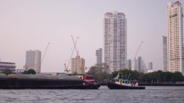 Küçük römorkör, Bangkok Tayland ve ufuk çizgisi yakınlarındaki Kaufaya Nehri 'ndeki büyük kum mavnasını itiyor - 4K Yatay