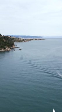 Deniz kıyısında, deniz kenarında, yatları ve yelkenlileri olan İHA, FullHD dikey