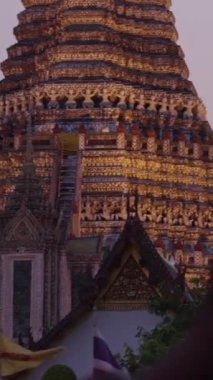 Gün batımında Bangkok Tayland 'daki Chao Phraya Nehri' nin renkli ışıklarıyla aydınlanan Wat Arun tapınağının yavaş çekim panoramik görüntüsü