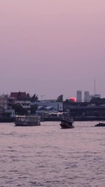 Işıklı teknelerin Bangkok Tayland 'da yoğun trafiğin olduğu köprünün yakınında dolaştığı Chao Reynaya nehrinden alacakaranlık.