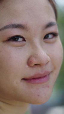 Islak yüzüyle kameraya bakıp gülümseyen genç bir kızın portresi.