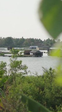 Suyun ortasında yüzen evler, rüzgarın savurduğu palmiye yaprakları arasında Vietnam Gölü, FullHD dikey