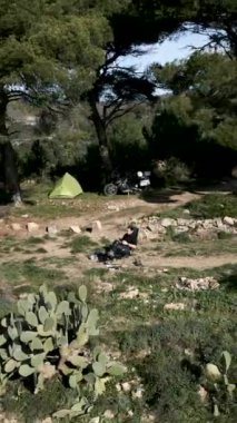 İnsansız hava aracı Fransa 'nın FullHD dikey ormanında motosiklet ve gezgin motorcunun çadırından uzaklaşıyor.