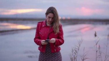 Kırmızı ceketli bir kadın kendini cep telefonuyla kaydediyor - 4K Yatay