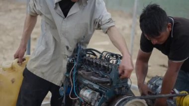 İki Vietnamlı tamirci kırsal alanda eski bir teknenin motorunu temizleyip tamir ediyorlar - 4K Yatay