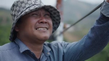 Vietnam 'da çalışırken şapka takmış, sigara içen Asyalı genç bir adamın portresi.