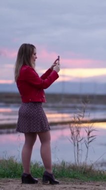 Beyaz güzel bir kadın akıllı telefonuyla bir video kaydediyor FullHD dikey