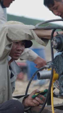 Elinde kerpetenle Vietnam 'da eski bir teknenin motorunu tamir eden genç bir tamirci.