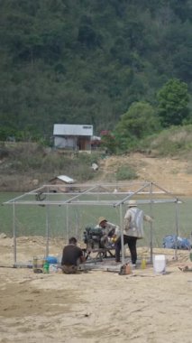 Vietnam 'daki ıssız bir gölün kıyısındaki eski bir teknenin motorunu tamir eden tamirciler.