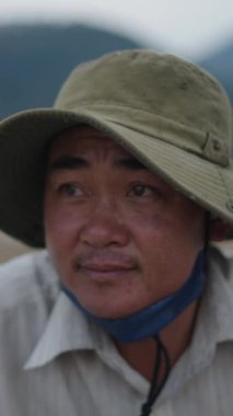 Genç Asyalı Vietnamlı bir çocuğun portresi kameraya bakıp gülümsüyor büyük bir şapka takıyor - FullHD Dikey