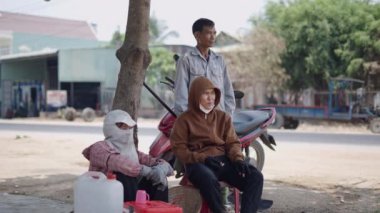 Üç Asyalı dinleniyor ve Vietnam 'da yolun kenarındaki bir ağacın altında sessizce sohbet ediyorlar - 4K Yatay