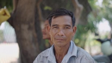 portrait of a mature asian man with a very sucai shirt and reeds in his hair looking at camera in vietnam - 4K Horizontal