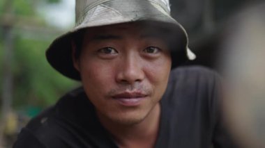 Kafasında şapka olan Asyalı bir çocuk kameraya dikkatlice bakıyor - 4K Yatay