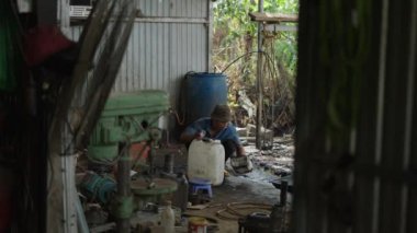 Genç Asyalı adam Vietnam 'da küçük bir atölyede çözücüyle filtreyi yıkıyor - 4K Yatay