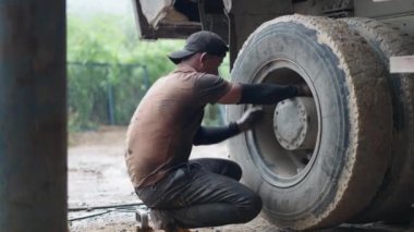 Çok kirli genç bir tamirci Vietnam 'da elleri ile büyük bir kamyon tekerleğinin cıvatalarını gevşetiyor - 4K Yatay