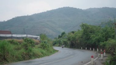 Vietnam dağları arasında yağmurlu bir günün ardından az trafiği olan kırsal yol - 4K Yatay