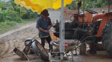 Kirli ve tehlikeli bir ortamda, Vietnam kırsalından bir tamirci yağmurda çalışıyor - 4K Yatay