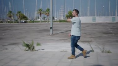 Palmiye ağaçları arasında çimento geçidi boyunca kameranın önünde yürüyen beyaz bir çocuk akıllı sesiyle bir ses notu gönderiyor - 4K Yatay Video