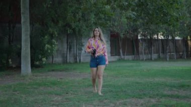 Genç esmer, beyaz bir kız kameraya doğru yürüyor ve sesli bir kitap okuyor - 4K Yatay