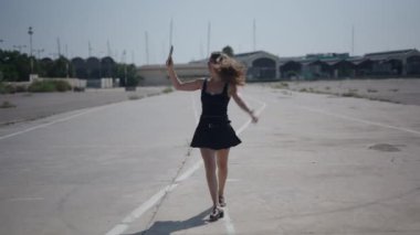 Beyaz, kısa siyah elbiseli genç bir kız liman yakınlarındaki endüstriyel banliyö bölgesinde kameraya doğru yürüyordu.