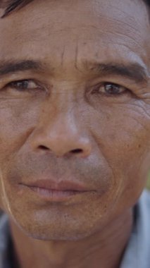 Vietnam 'da gülümsemeden kameraya ciddi ciddi bakan olgun Asyalı bir adamın portresi.