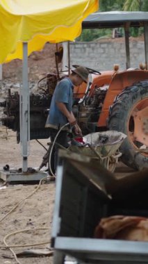 Vietnam 'da yağmurlu bir günde kirli bir ortamda, dışarıda, şemsiye altında çalışan tamirci FullHD Dikey