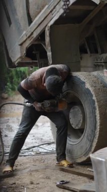 Ağzında sigara ve şapkası olan genç bir tamirci Vietnam 'da bir kamyon tekerleğinin cıvatalarını gevşetiyor.