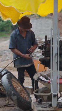 Kirli ve tehlikeli bir ortamda, Vietnam 'ın kırsal kesimlerinden bir tamirci açık havada çalışıyor.