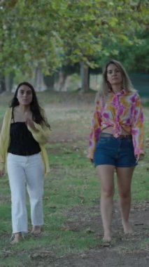 Biri esmer, biri sarışın olmak üzere iki beyaz kız kameraya doğru çıplak ayakla yürüyorlar ve onlara yaklaşmalarını işaret ediyorlar.