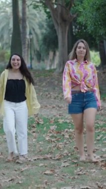 İki beyaz kız, bir esmer ve bir sarışın kameraya doğru çıplak ayakla yürüyorlar jestler ve jestler yapıyorlar FullHD dikey