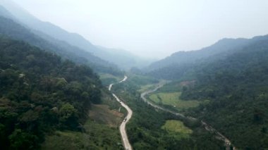 Vietnam 'daki dağlarla ağaçlar arasında nehir kıyısındaki vadiyi geçen yol - 4K Yatay