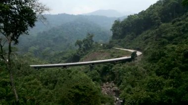 Nehir üzerindeki köprüde küçük bir motosiklet ve Vietnam 'daki dağlar - 4K Yatay