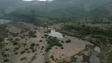 Vietnam 'daki kurak nehrin üzerindeki ağaçlar ve dağlar arasındaki vadiden drone görüntüsü - 4K Yatay