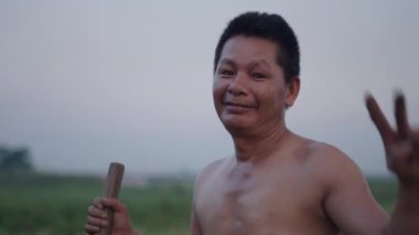 Çalışırken kameraya el sallayan ve gülümseyen terli Vietnamlı bir çiftçinin portresi - 4K Yatay