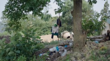Vietnam 'da çöplerle çevrili küçük bir beton karıştırıcının yanındaki evin bahçesinde asılı giysiler - 4K Yatay