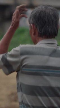 Kamera, yetişkin bir Vietnamlı erkek çiftçinin bahçedeki çalışma günü boyunca attığı adımları takip ediyor.